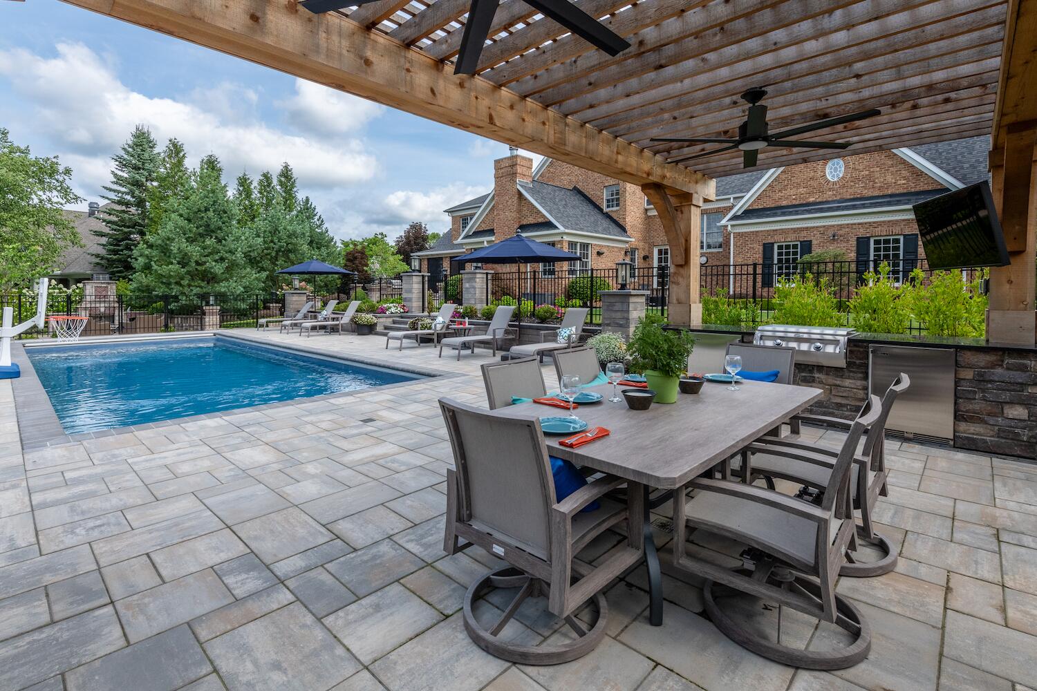 Fully equipped outdoor kitchen with a stone-clad bar and built-in appliances in Gates Mills, OH